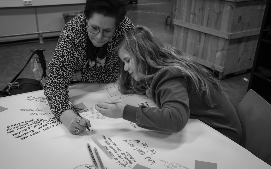 Sandra en dochter Wies schrijven hun antwoorden op de vragen op het vel.